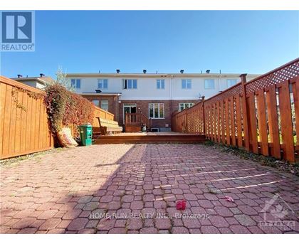 A brick pathway leads to a wooden fence and a building.