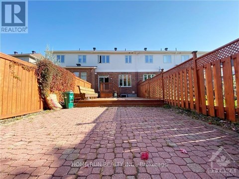 A brick pathway leads to a wooden fence and a building.