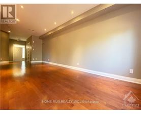 A spacious room with wooden flooring and a hallway leading to another room.