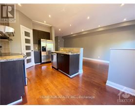 A kitchen with dark wood floors and white walls.