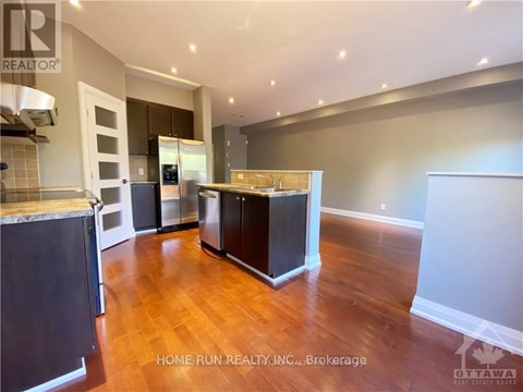 A kitchen with dark wood floors and white walls.