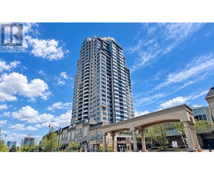 A tall building with a glass facade stands in front of a clear blue sky.
