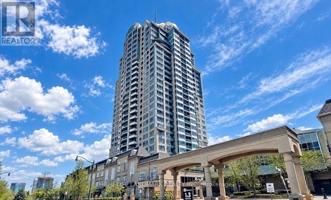A tall building with a glass facade stands in front of a clear blue sky.