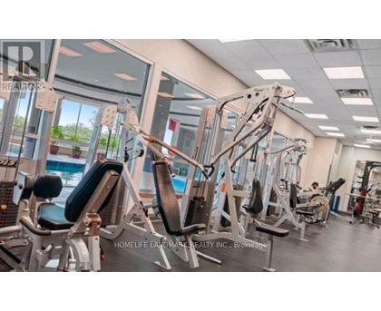 A gym with various exercise machines and a person working out in the background.