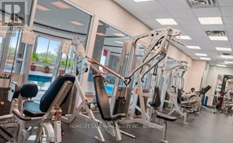 A gym with various exercise machines and a person working out in the background.