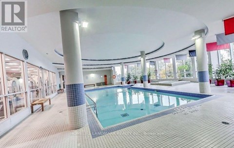 A large indoor swimming pool with a tiled edge and a bench to the side.