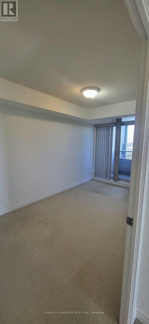 A room with a carpeted floor and a window with curtains.