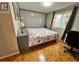 A bedroom with a floral bedspread and a wooden floor.
