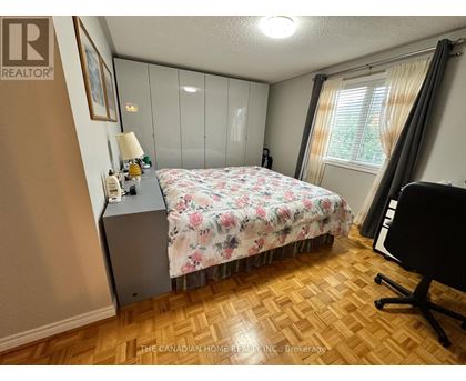 A bedroom with a floral bedspread and a wooden floor.