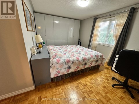 A bedroom with a floral bedspread and a wooden floor.