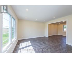 A spacious room with wooden flooring and a large window.