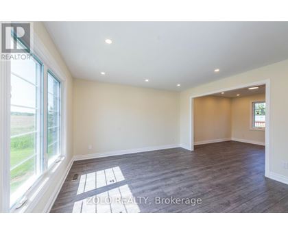 A spacious room with wooden flooring and a large window.