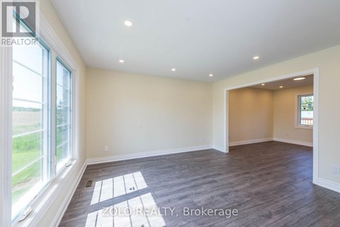 A spacious room with wooden flooring and a large window.
