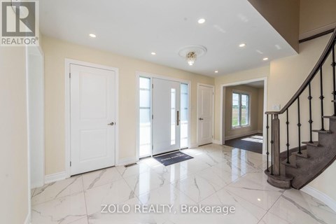 A spacious foyer with marble flooring and a staircase.