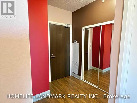 A hallway with a red wall and a brown wall with a door and a mirror.
