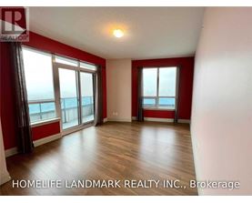 A room with red walls and wooden flooring, with a large window overlooking the ocean.