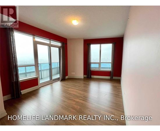A room with red walls and wooden flooring, with a large window overlooking the ocean.