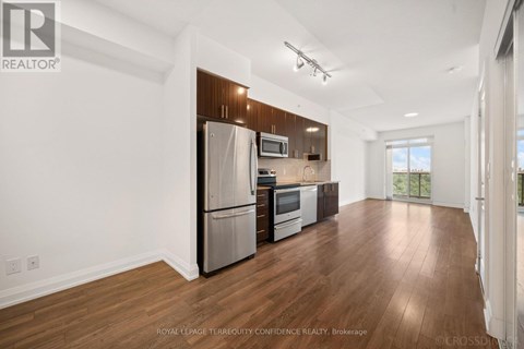 A spacious kitchen with wooden floors and stainless steel appliances.