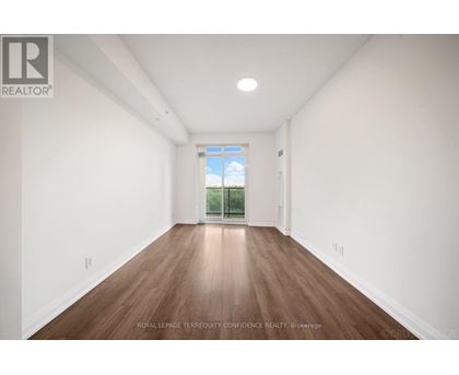 A room with wooden floors and white walls, with a window that shows a blue sky and greenery outside.