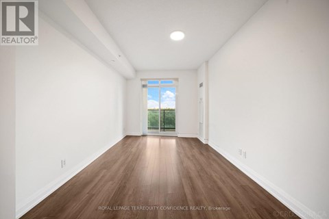 A room with wooden floors and white walls, with a window that shows a blue sky and greenery outside.