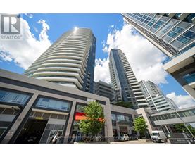 A modern building with a curved facade stands tall among other buildings.
