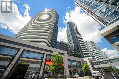 A modern building with a curved facade stands tall among other buildings.