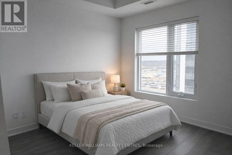A bedroom with a large bed and a window with blinds.