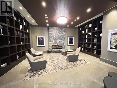 A living room with a rug, two chairs and a fireplace.