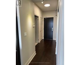 A hallway with a black door and white walls.