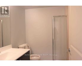 A white bathroom with a toilet, sink, and shower door.
