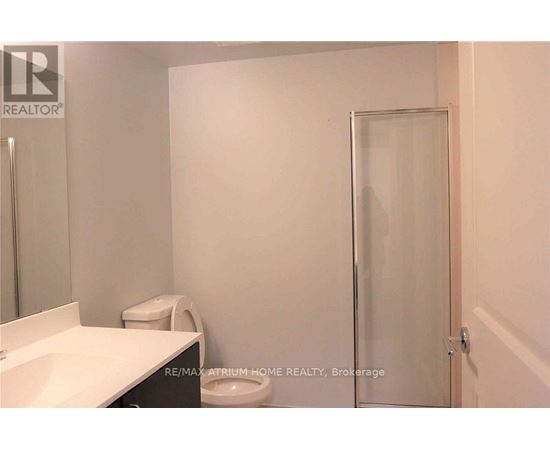 A white bathroom with a toilet, sink, and shower door.