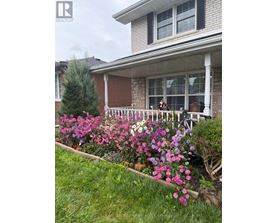 A house with a white porch and a flower bed in front.