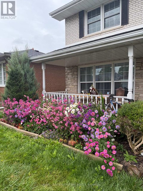 A house with a white porch and a flower bed in front.