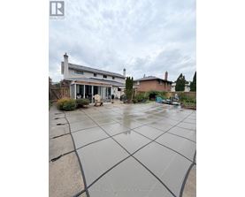 A wet backyard with a house and a car in the background.