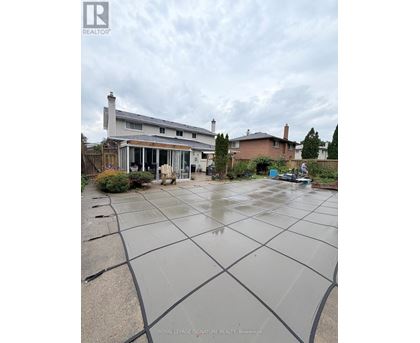 A wet backyard with a house and a car in the background.