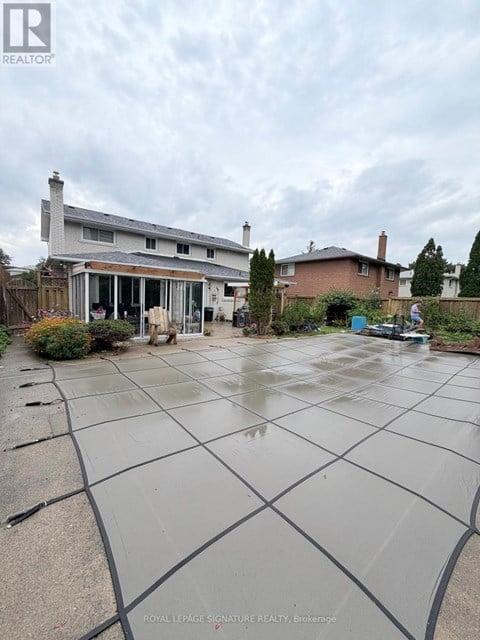 A wet backyard with a house and a car in the background.