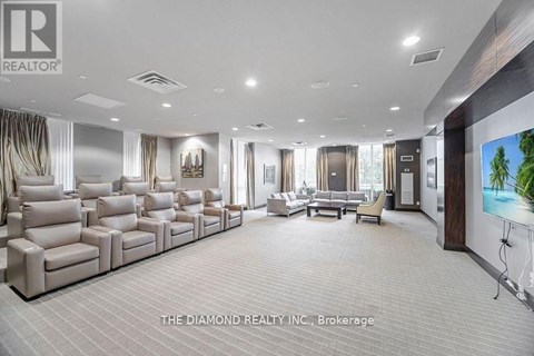 A spacious living room with a row of beige sofas and a television on the wall.