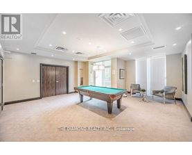 A room with a pool table and chairs.