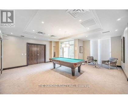 A room with a pool table and chairs.