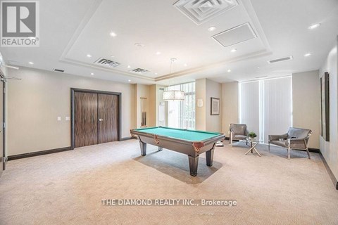 A room with a pool table and chairs.