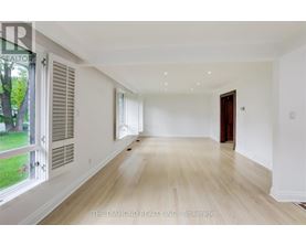 A spacious room with wooden flooring and white walls.