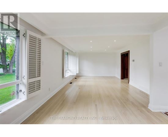 A spacious room with wooden flooring and white walls.