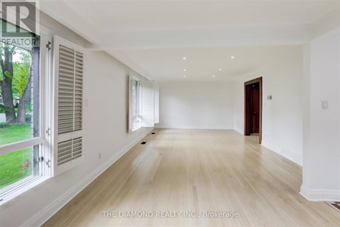 A spacious room with wooden flooring and white walls.