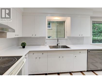 A modern kitchen with white cabinets and a diamond logo on the counter.