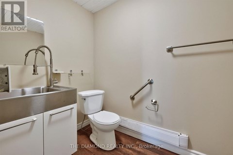 A bathroom with a toilet, sink, and grab bar.