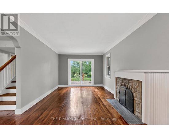 A room with a fireplace and a view of trees through the door.