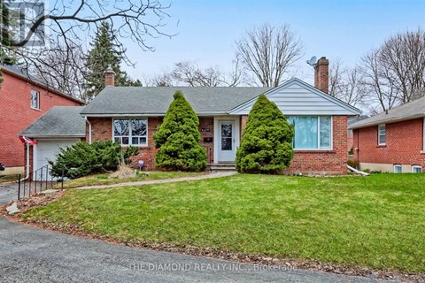 A house with a red brick exterior and a white door is surrounded by a green lawn.