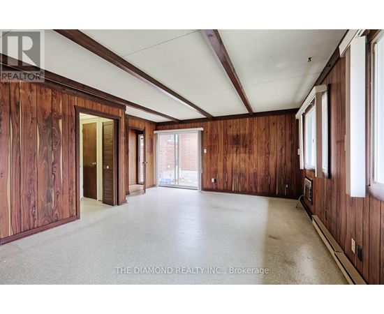 A large empty room with wooden walls and a white ceiling.