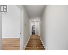 A long hallway with a door on the left and a bedroom at the end.