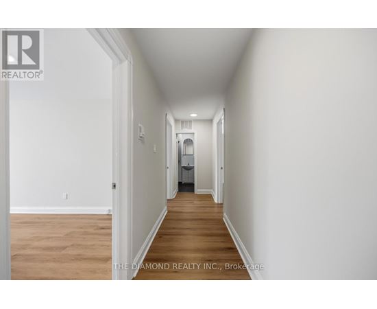 A long hallway with a door on the left and a bedroom at the end.